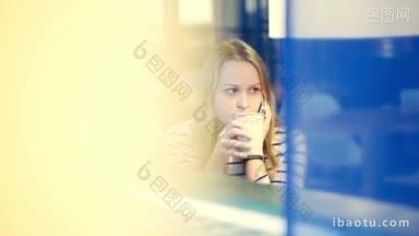 咖啡馆里的年轻女子一边喝茶或喝咖啡一边打电话，透过窗户可以<strong>看到</strong>窗外的灯光